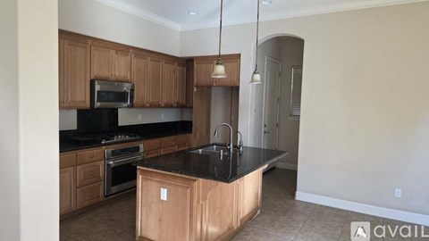 A kitchen with wooden cabinets and black countertops.