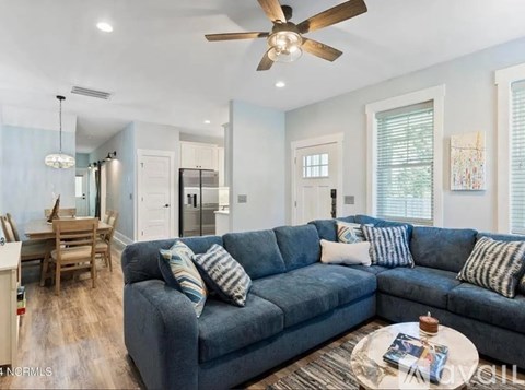 A living room with a blue couch and a ceiling fan.