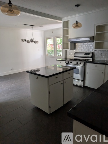 A kitchen with white cabinets and black countertops.