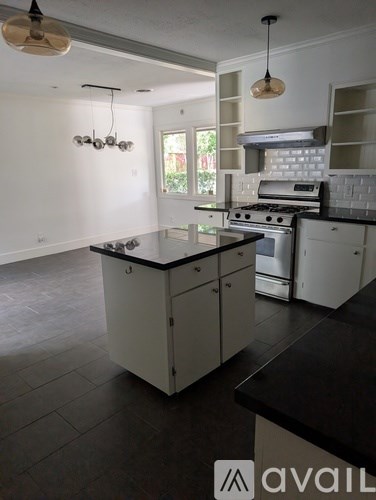 A kitchen with white cabinets and black countertops.