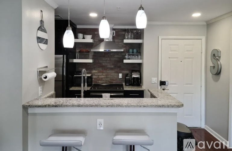 A kitchen with a granite countertop and white stools.