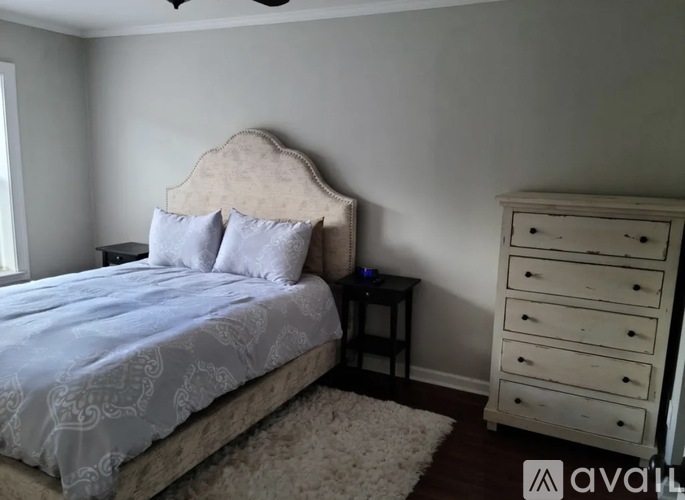 A bedroom with a bed, nightstand, and dresser.