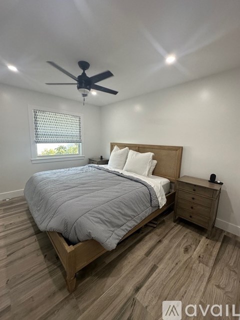 A bedroom with a bed, nightstand, and a ceiling fan.
