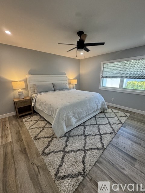 A bedroom with a large bed and a ceiling fan.