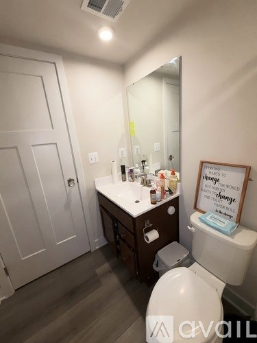 A bathroom with a toilet, sink, mirror, and a sign that says "Change to Change the World".