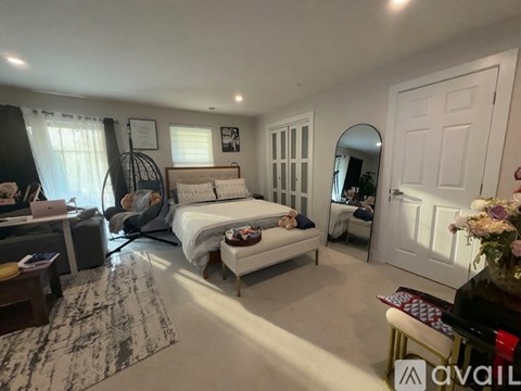 A well-lit bedroom with a large bed, a desk, and a chair.