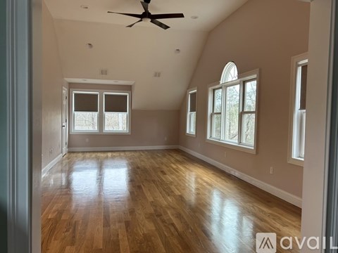 A spacious room with wooden floors and a ceiling fan.