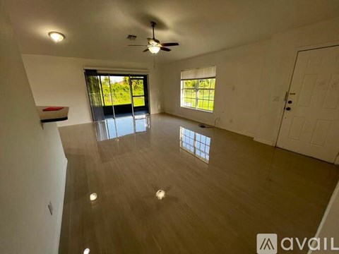 A spacious room with wooden flooring and a ceiling fan.