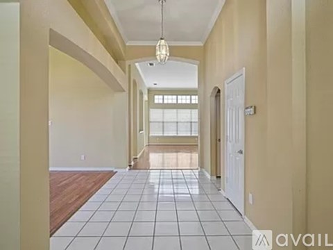 A long hallway with a tiled floor and a chandelier hanging from the ceiling.