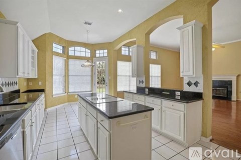 A kitchen with white cabinets and black countertops.