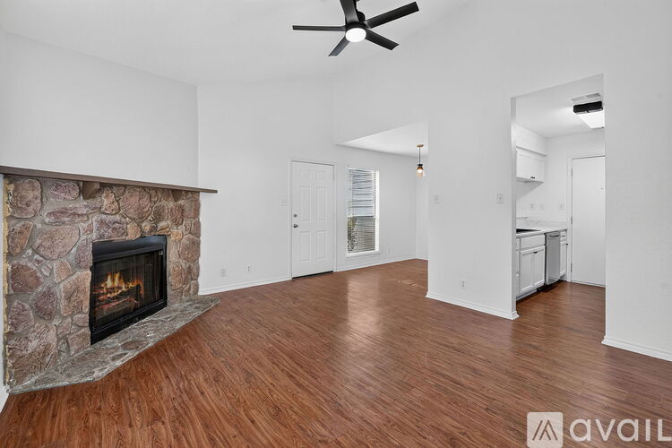 A living room with a stone fireplace and hardwood floors.