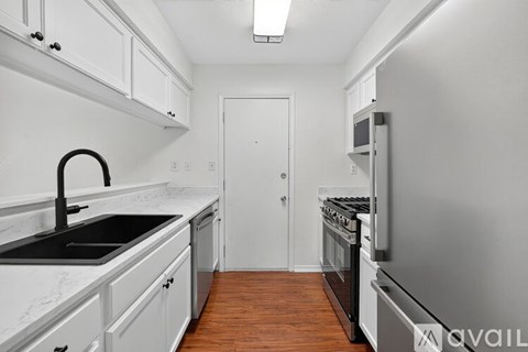 A kitchen with white cabinets and a black sink.