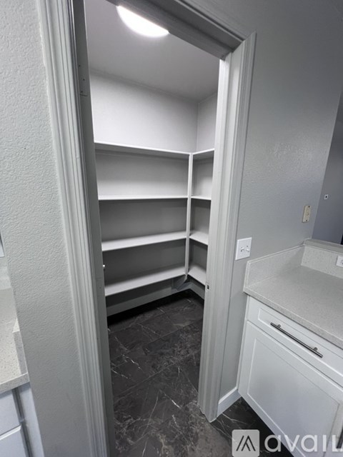 A kitchen pantry with white cabinets and marble flooring.