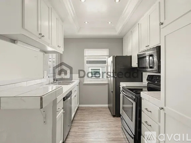 A kitchen with white cabinets and black appliances.