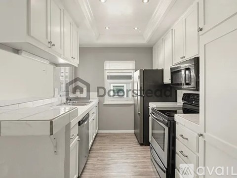 A kitchen with white cabinets and black appliances.