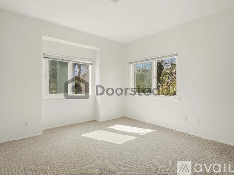 A spacious room with a large window on the right and a smaller window on the left.