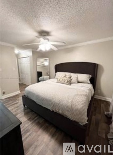 A bedroom with a bed, a ceiling fan, and a nightstand.