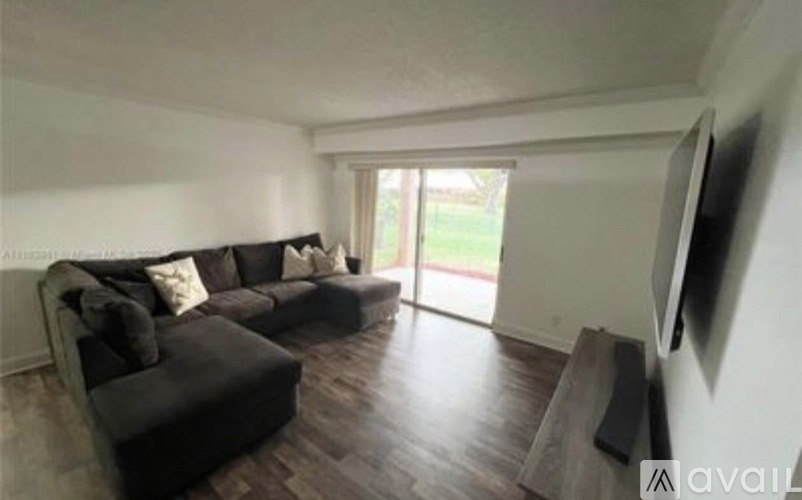 A living room with a black couch and a television on the wall.