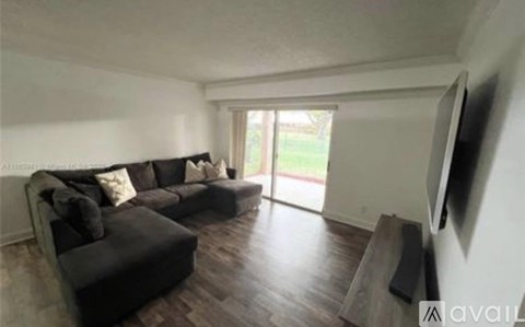 A living room with a black couch and a television on the wall.