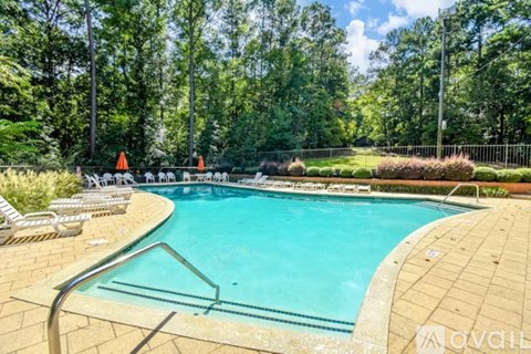 A pool surrounded by trees and chairs.