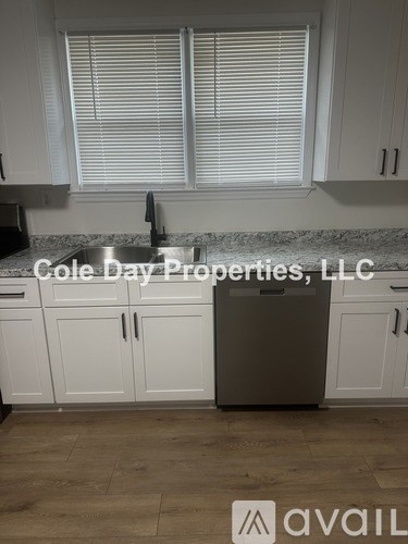 A kitchen with white cabinets and a marble countertop.