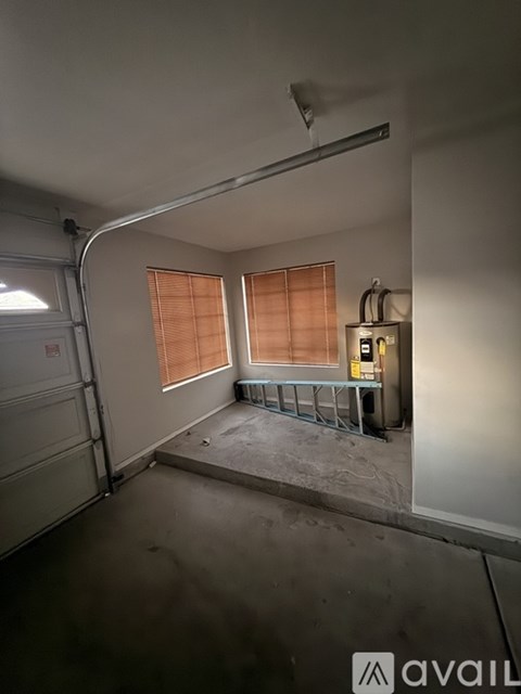 A room with a concrete floor and a window with wooden blinds.