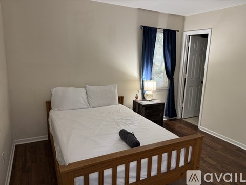 A bedroom with a bed, nightstand, and window with blue curtains.
