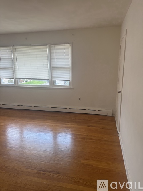 A room with wooden floors and a window with blinds.