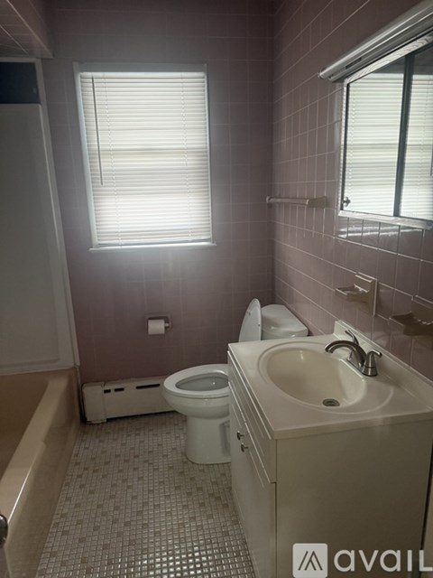 A bathroom with a toilet, sink, and window.