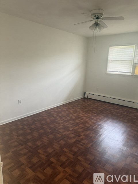 A room with a ceiling fan and wooden flooring.