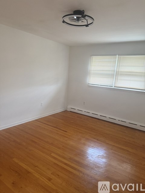 A room with wooden flooring and a window with blinds.