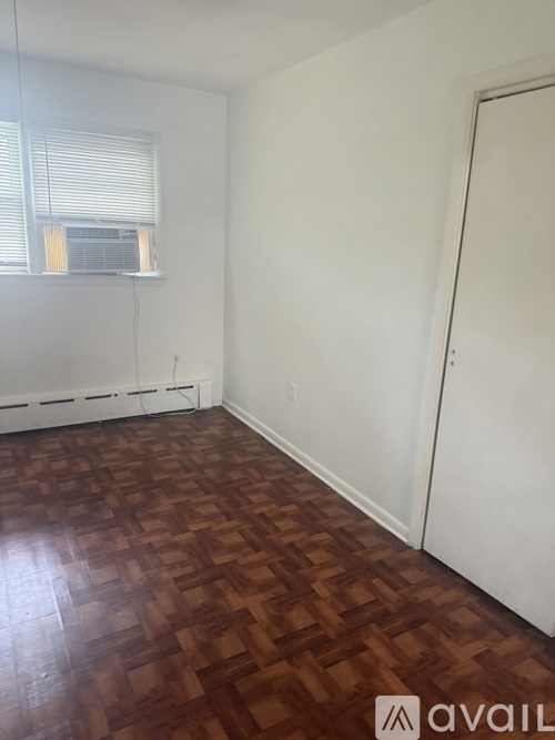 A room with a wooden floor and a window with blinds.