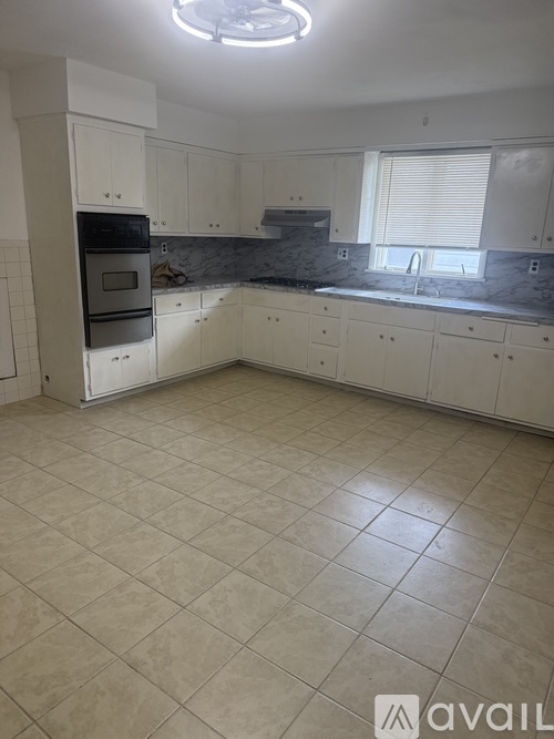 A kitchen with white cabinets and a tiled floor.
