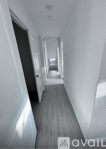 A long hallway with white walls and wood flooring.