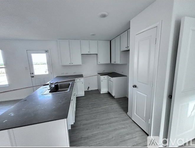A kitchen with white cabinets and a black countertop.