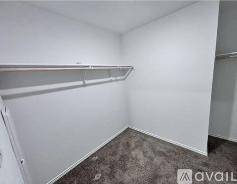 A small, empty room with a carpeted floor and a metal shelf.