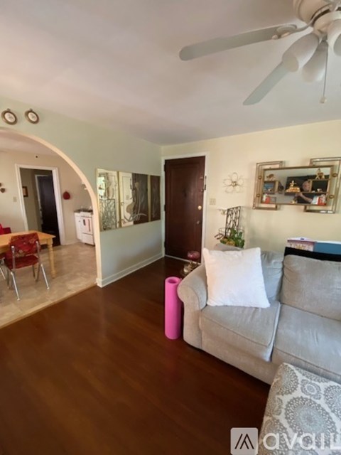 A living room with a grey couch and a pink stool.