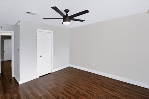 A room with a ceiling fan and wood flooring.