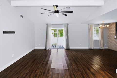 A room with a ceiling fan and a view of trees through the window.