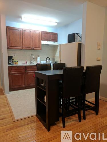 A kitchen with wooden cabinets and a black table with four chairs.