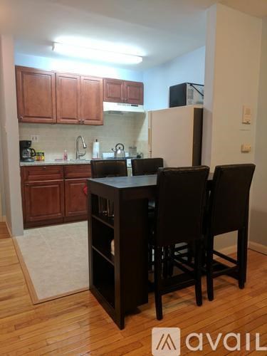 A kitchen with wooden cabinets and a black table with four chairs.