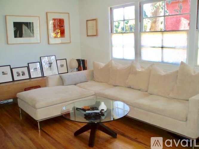 A living room with a white couch, a glass coffee table, and pictures on the wall.