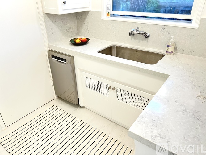 A white kitchen with a sink and a window.