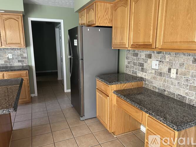 A kitchen with a refrigerator and wooden cabinets.