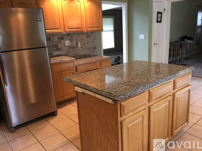 A kitchen with a granite countertop and wooden cabinets.