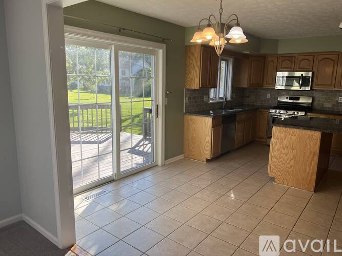 A kitchen with a large island and a sliding glass door leading to a backyard.