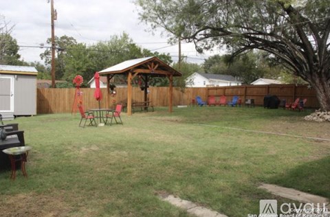 A backyard with a gazebo, chairs, and a fence.