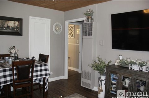 A dining room with a checkered tablecloth and a wooden cabinet with the word HOME on it.