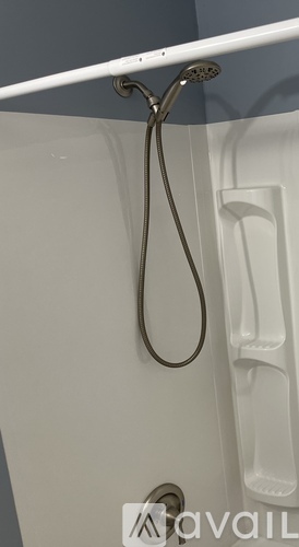 A shower head is mounted on a white bathtub.