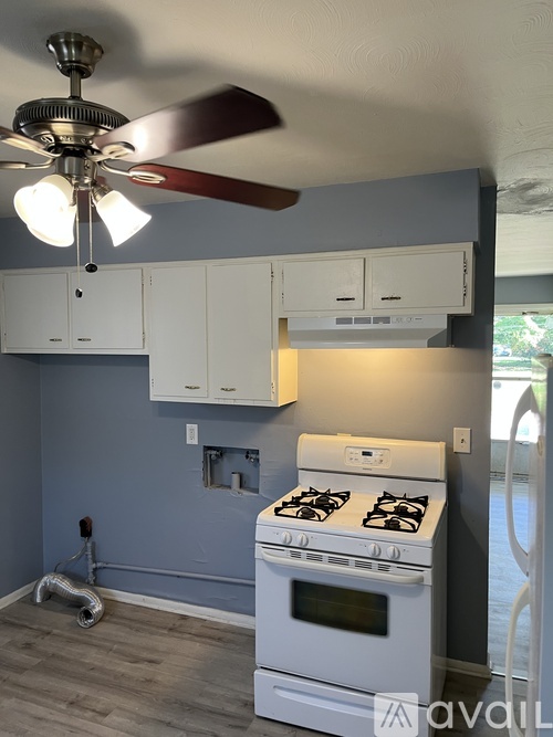 A kitchen with a white stove and a ceiling fan.
